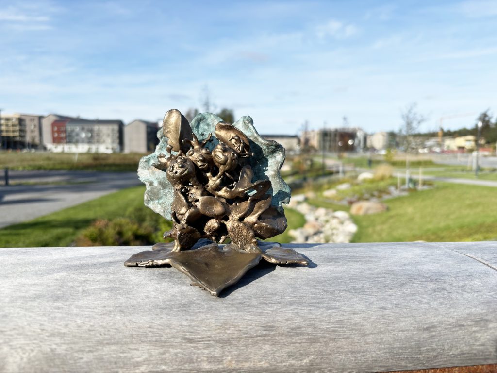 Foto. Liten staty på broräcke.