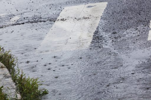 Regn och vattenpöl på asfalt