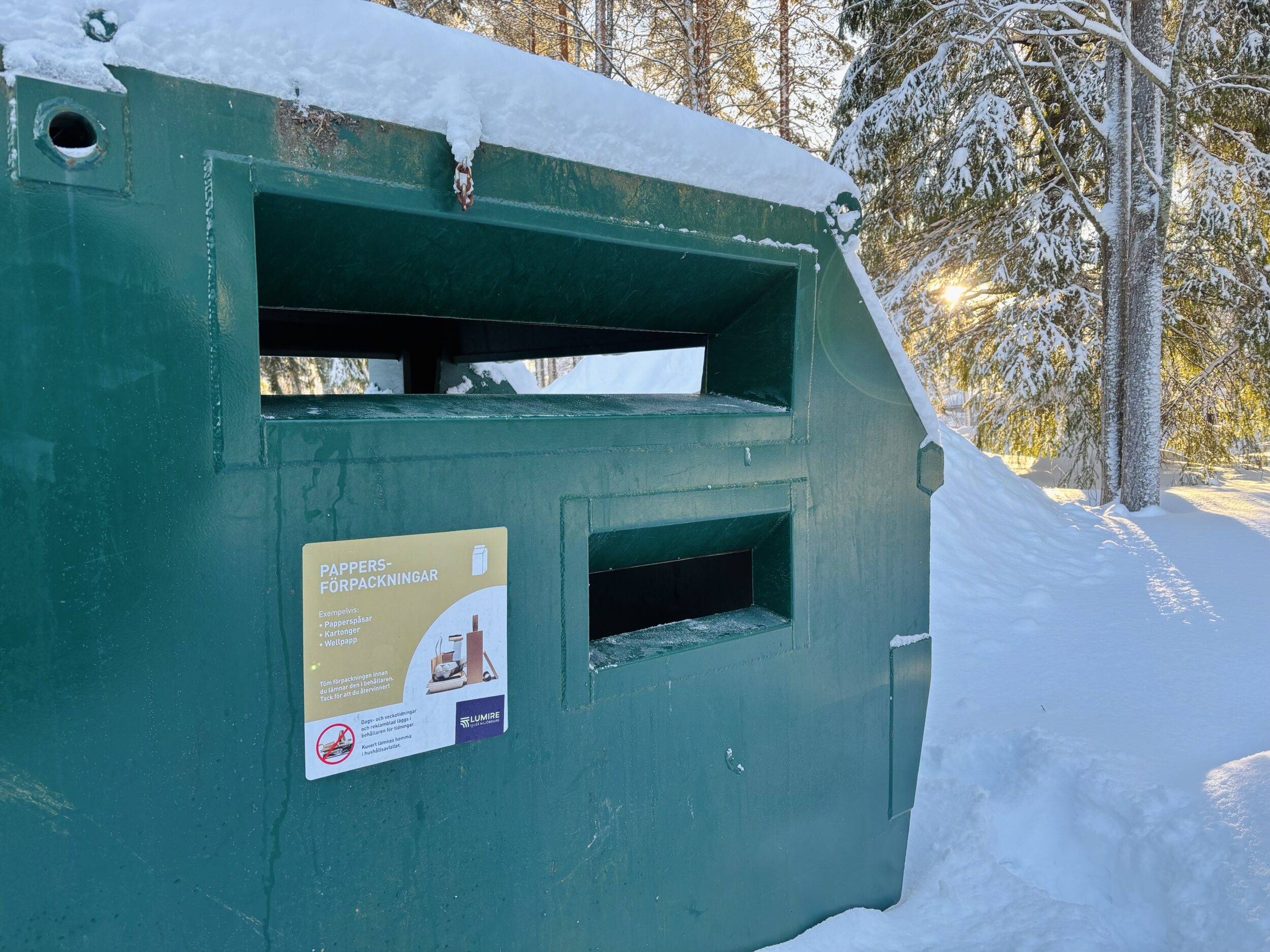 Foto. Grön behållare för återvinning av pappersförpackningar.