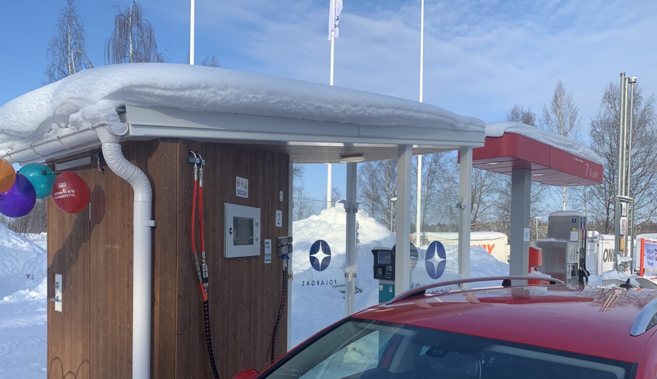 Bild på en tankstation för biogas, i förgrunden står en röd bil.
