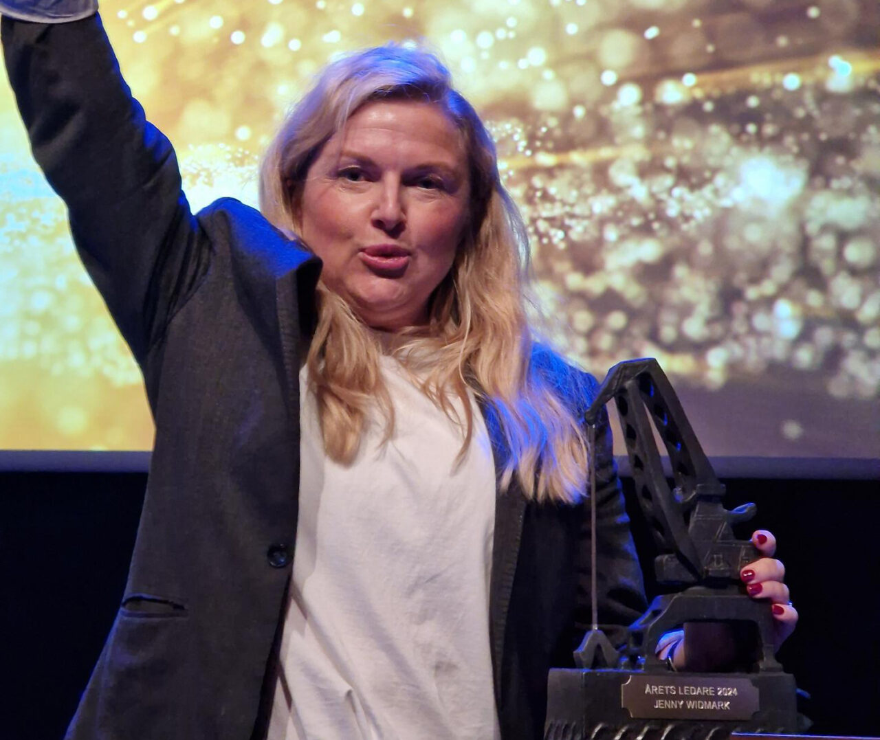 Jenny Widmark står på scenen bredvid sin prisstatyett.